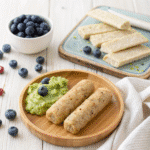 Dairy-free porridge fingers served with mashed avocado and fresh blueberries on a bamboo baby plate